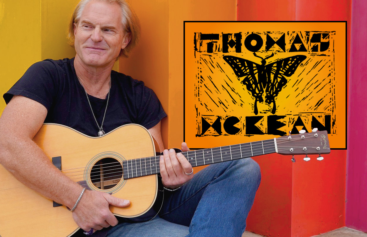 A smiling middle aged man with blond hair holding a guitar. "Thomas McKean" and a butterfly in woodcut logo.